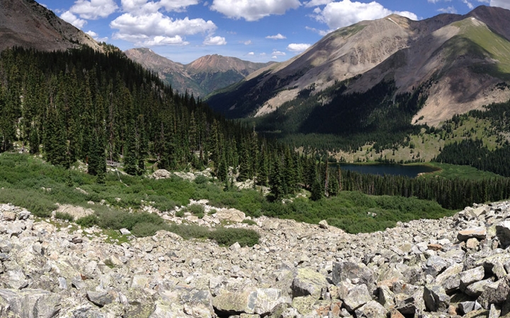 a rocky mountain landscape with rocks, grassy, trees and mountains